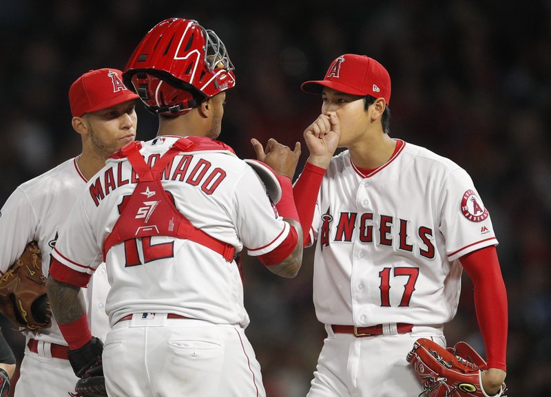 Los Angeles Angels starting pitcher Shohei Ohtani, right, of Japan, and Andrelton Simmons, left, listen to catcher Martin Maldonado during the second inning of a baseball game against the Boston Red Sox, Tuesday, April 17, 2018, in Anaheim, Calif. (AP Photo/Jae C. Hong)