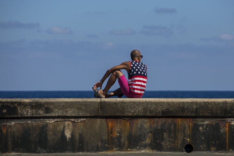 A man wearing a shirt with the stars and stripes sits on the Malecon in Havana, Cuba, Wednesday, April 18, 2018. Cuba's legislature opened today a two-day session that is to elect a successor to President Castro. (AP Photo/Desmond Boylan)