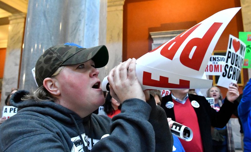 In this March 9, 2018, file photo, Nema Brewer, an employee of the Fayette County School District, uses a protest sign as a makeshift bullhorn to shout at the Kentucky Senate chambers in protest of Kentucky Senate Bill 1, in Frankfort, Ky. The public education uprisings that began in West Virginia and spread to Arizona, Oklahoma and Kentucky share similar origin stories. Teachers, long tired of low wages and a dearth of state funding, begin talking to each other online. Their Facebook groups draw tens of thousands of members. They share stories of their frustrations and then they demand change. 