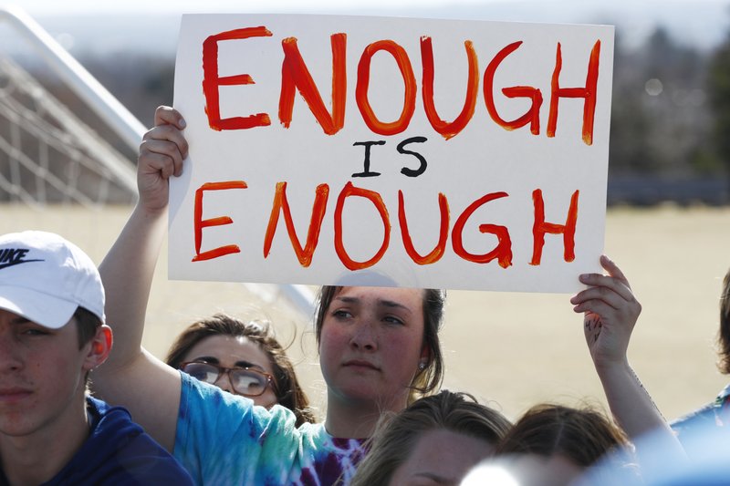 In this March 14, 2018, file photograph, 15-year-old Leah Zundel waves a placard during a student walkout to protest gun violence on the soccer field behind Columbine High School in Littleton, Colo. Students at high schools across the country are expected to walk out of classes Friday, the 19th anniversary of the Columbine shooting, in their latest push for gun control. But they won’t be protesting at the Colorado school where the violence took place. 