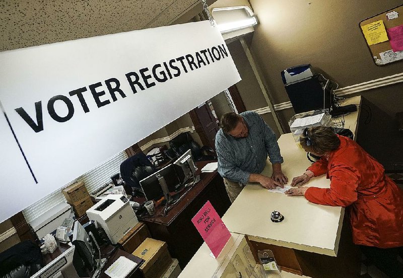 Voter registration clerk Bart Moreland (left) helps Little Rock resident Ginny McMurry change the address on her voter registration Thursday at the Pulaski County county clerk’s office in Little Rock. Monday is the deadline to register to vote in the May 22 primary and nonpartisan judicial elections. 