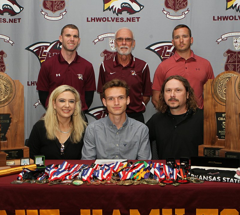 The Sentinel-Record/Richard Rasmussen RUNNING RED: Lake Hamilton' Cody Weldon, sitting center, signed a national letter of intent to run track and cross country for Arkansas State University Wednesday in the Alumni Room at Wolf Arena. Joining Weldon, in front, from left, were his mother Holly Weldon and father David Weldon, and back, from left, coach Brandon Smith, coach Karl Koonce and coach Brandon Starr.