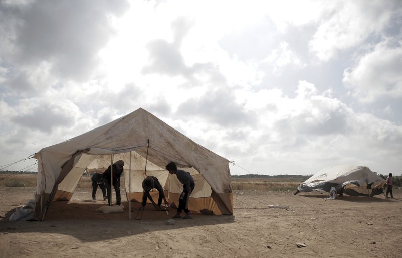 Palestinian protesters set up tents at the Gaza Strip's border with Israel, Thursday, April 19, 2018. Palestinian activists are moving protest encampments closer to Israel's fence ahead of mass demonstration. (AP Photo/ Khalil Hamra)