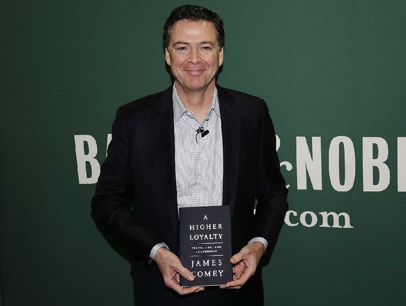 Former FBI Director James Comey poses with his new book during an appearance Wednesday at a Barnes & Noble in New York. 
