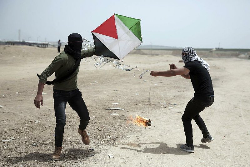 Palestinian protesters in Gaza on Friday fly a kite dangling a burning rag as part of a new tactic aimed at setting fields afire on the Israeli side of the border. 
