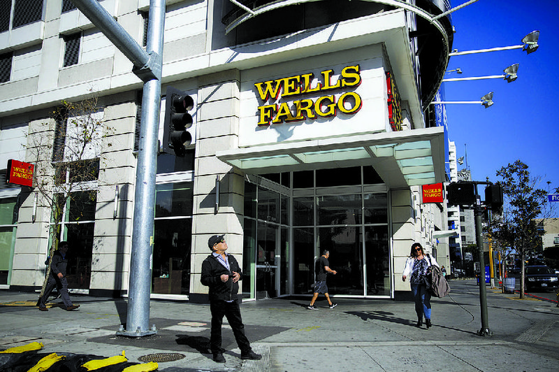 People pass a Wells Fargo bank in Los Angeles on Thursday. The banking company was hit with a $1 billion civil penalty Friday by federal regulators over “reckless, unsafe or unsound practices and violations of law” that cost customers millions of dollars. Some customers had cars wrongfully repossessed. 
