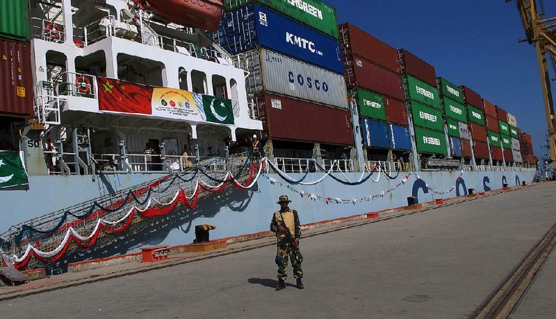 In this photo taken in late 2016, a serviceman stands guard while a loaded Chinese ship prepares to leave the Gwadar port in Pakistan.  