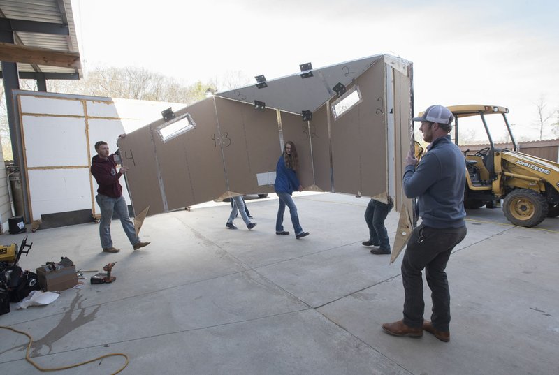 NWA Democrat-Gazette/SPENCER TIREY Daniel Earls (right) works Friday with other University of Arkansas at Little Rock construction management students to carry their rapidly deployable emergency disaster shelter they designed onto an earthquake simulator for testing at John Brown University's technology center in Siloam Springs.