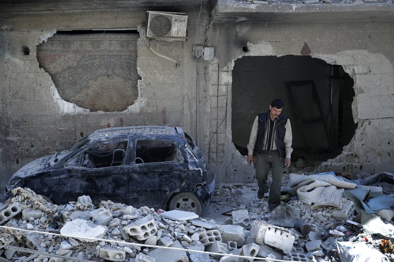 In this Monday, April 16, 2018 photo, man walks just meters away from where the alleged chemical weapons attack occurred in the town of Douma, the site of a suspected chemical weapons attack, near Damascus, Syria. The survivors blamed the attack on the Army of Islam, the powerful rebel group that controlled the town before it was taken over by Syrian government forces this week, although they did not offer evidence to back up their claims. (AP Photo/Hassan Ammar)