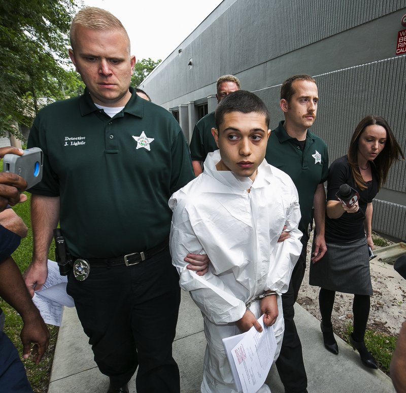 Marion County Sheriff's Detectives John Lightle, left, and Dan Pinder, right, escort a handcuffed and shackled Sky Bouche, 19, center, to a waiting patrol car, Friday, April 20, 2018, in Ocala, Fla. Bouche is the suspect in a shooting that occurred at Forest High School Friday morning. 