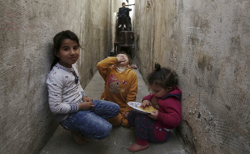 Children eat in an alley Saturday outside the residence of Mohammed Ayyoub, 14, in the Jebaliya refugee camp, Gaza Strip, as relatives mourn his death. 

