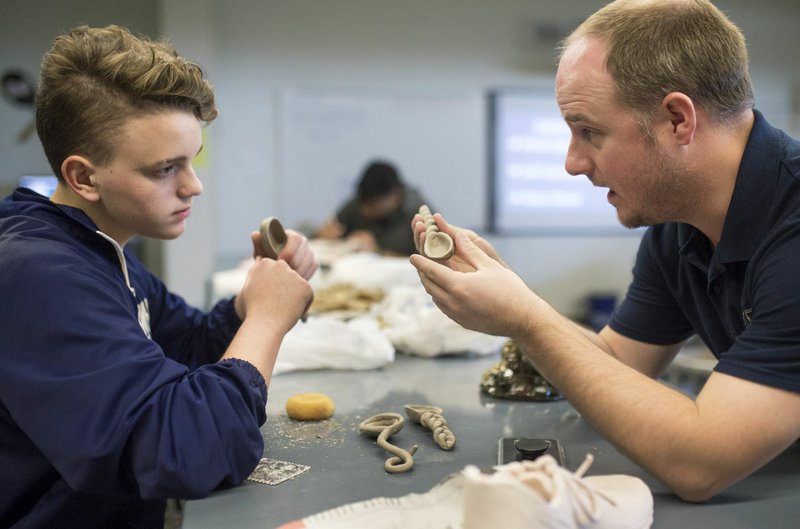 NWA Democrat-Gazette/CHARLIE KAIJO Hunter Alexander (right) helps Parker Judd, 15, with a project April 12 at Bentonville West High School in Centerton. Alexander, an art teacher and tennis coach at Bentonville West High School, moved to the area from Oklahoma in 2016.