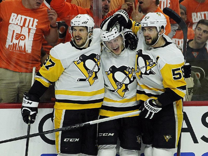 Pittsburgh Penguins center Jake Guentzel (center) celebrates with teammates Sidney Crosby (left) and Kris Letang (right) after scoring in the third period Sunday in Philadelphia. Guentzel scored four goals in the Penguins’ 8-5 victory over the Philadelphia Flyers. 