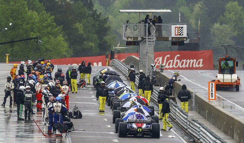 IndyCar drivers stand around on pit road as the Indy Grand Prix of Alabama was red flagged due to rain Sunday. The race will resume today in Birmingham, Ala. 