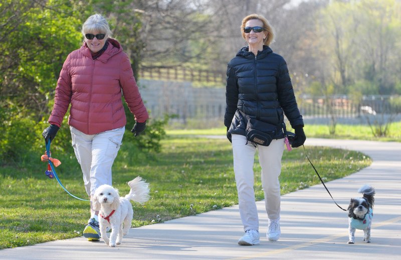 Kathleen Barta (left) with Frisco and Marianne Neighbors with Perky walk April 10 on the Razorback Greenway near Sanders Avenue in Springdale. The city is considering other projects to connect trails throughout Springdale to the Greenway.