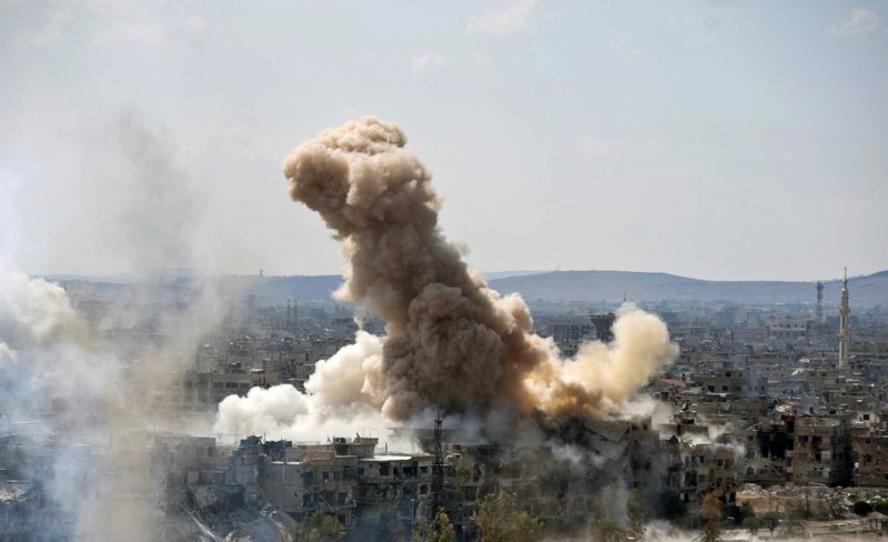 In this photo released by the Syrian official news agency SANA, smoke rises after Syrian government airstrikes and shelling hit in Hajar al-Aswad neighborhood held by Islamic State militants, southern Damascus, Syria, Sunday, April 22, 2018. Syrian state media says government forces are pounding districts of southern Damascus held by Islamic State militants with warplanes, helicopters and artillery in a bid to enforce an evacuation deal reached earlier in the week. (SANA via AP)