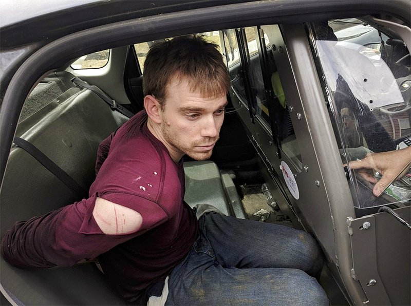 In this photo released by the Metro Nashville Police Department, Travis Reinking sits in a police car after being arrested in Nashville, Tenn., on Monday, April 23, 2018. 