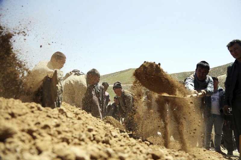 Afghan men bury a victim of Sunday’s suicide attack at a voter registration center, in Kabul, Afghanistan, on Monday. 
