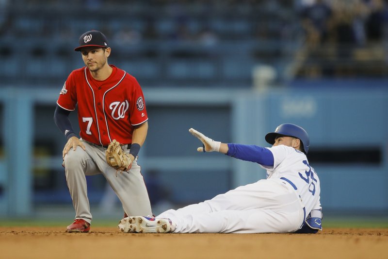 Los Angeles Dodgers' Cody Bellinger, right, gestures after taking second base on his RBI double as Washington Nationals' Trea Turner kneels on the field during the sixth inning of a baseball game, Sunday, April 22, 2018, in Los Angeles. (AP Photo/Jae C. Hong)