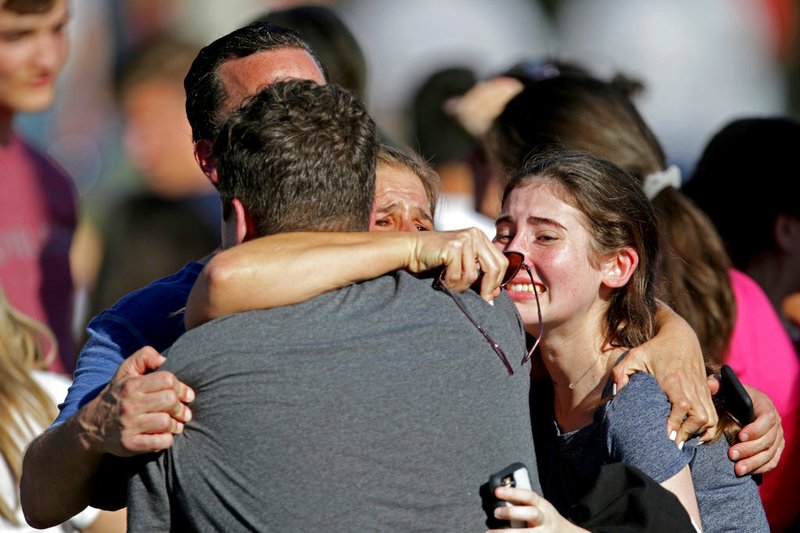 In this Wednesday, Feb. 14, 2018, file photo, a family reunites following a shooting at Marjory Stoneman Douglas High School in Parkland, Fla. A commission tasked with investigating government actions surrounding the Florida high school massacre and the state’s other mass shootings is set to hold its first meeting, Tuesday, April 24. (John McCall/South Florida Sun-Sentinel via AP, File)