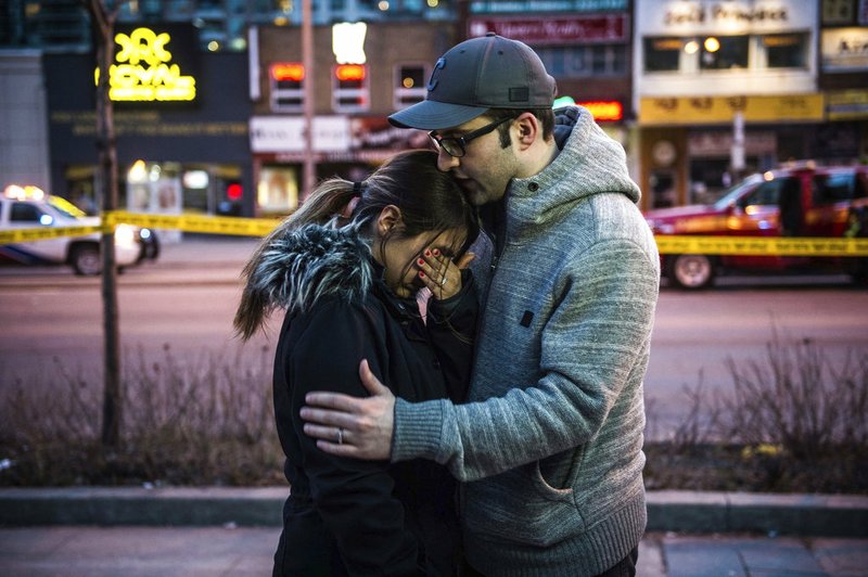 Farzad Salehi consoles his wife, Mehrsa Marjani, who was at a nearby cafe and witnessed the aftermath when a van plowed down a crowded sidewalk, killing multiple people and injuring others, Monday, April 23, 2018, in Toronto. (Aaron Vincent Elkaim/The Canadian Press via AP)