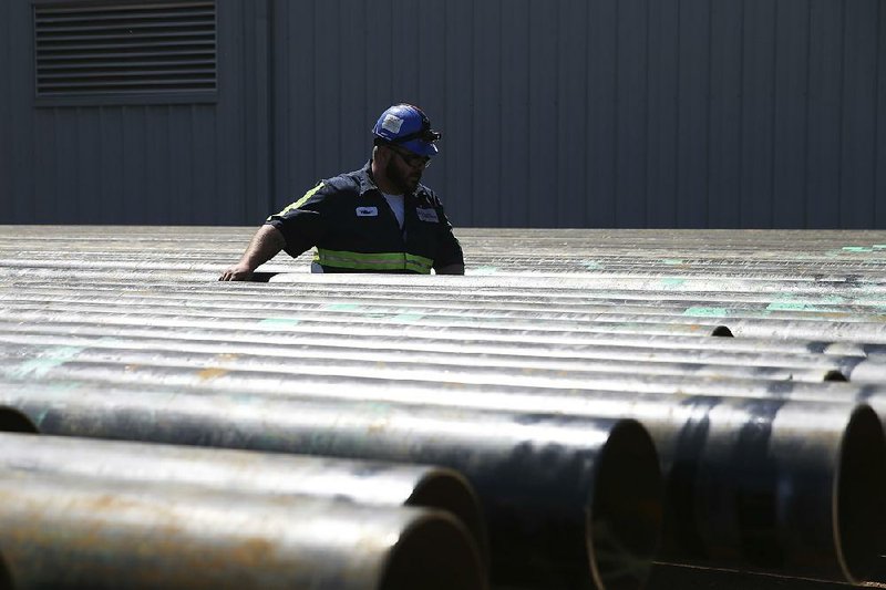 William Hampton walks between steel pipes Monday at the Borusan Mannesmann Pipe plant in Baytown, Texas. The company says the future of the plant is murky unless it gets a waiver if proposed U.S. tariffs are imposed.  