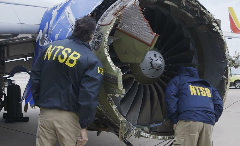 In this photo provided by the National Transportation Safety Board, investigators examine a Southwest Airlines plane engine last week that blew apart in midair.  