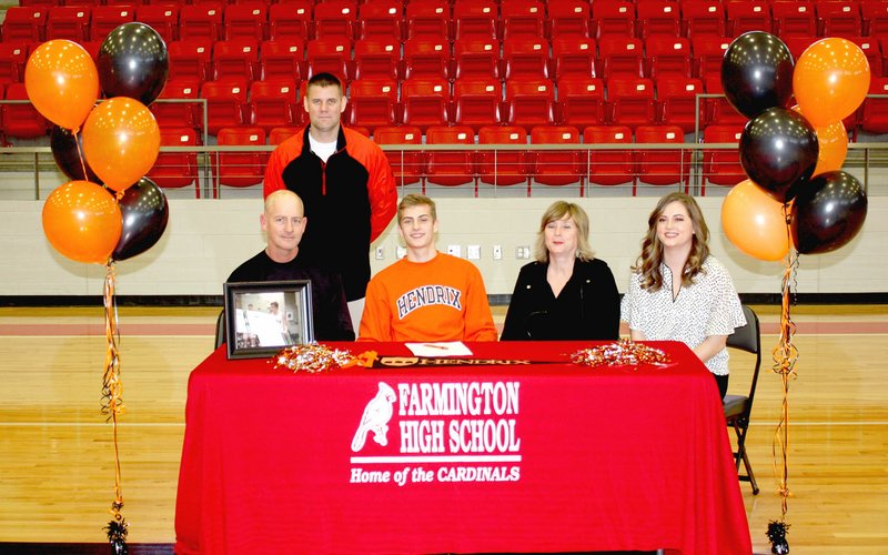 MARK HUMPHREY ENTERPRISE-LEADER Farmington senior Peyton Maxwell (center in orange) celebrated signing a national letter of intent to play men's college basketball for Hendrix College, of Conway, Thursday, April 13, 2018, at Cardinal Arena. Accompanying Peyton was his family (from left): Bill Maxwell, father; Farmington boys basketball coach Beau Thompson (standing); Peyton; Heather Maxwell, mother; and Haley Maxwell, sister, a 2014 Farmington graduate.