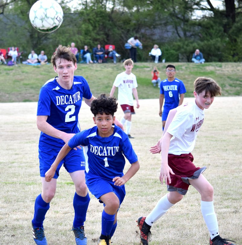 Westside Eagle Observer/MIKE ECKELS Seth Rich (Decatur 2), Kelvin Moreno (Decatur 2), and Seth Weaver (right) chase down a ball that was launched into the air by Moreno during the second half of the Decatur-Life Way soccer match in Centerton April 17.