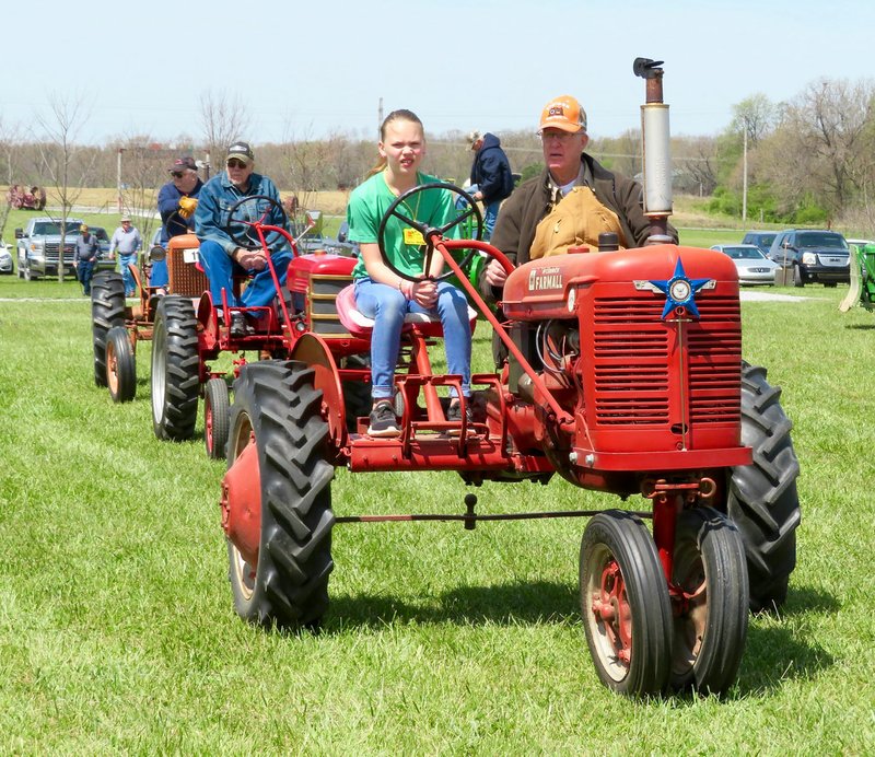 Westside Eagle Observer/RANDY MOLL Hailey Hodson, 10, of Bentonville, got a lesson from Glenn Smith of Gentry in tractor driving on one of his two-seater, double-controls tractors during the parade of power at noon on Friday (April 20, 2018) at the spring show of the Tired Iron of the Ozarks in Gentry.