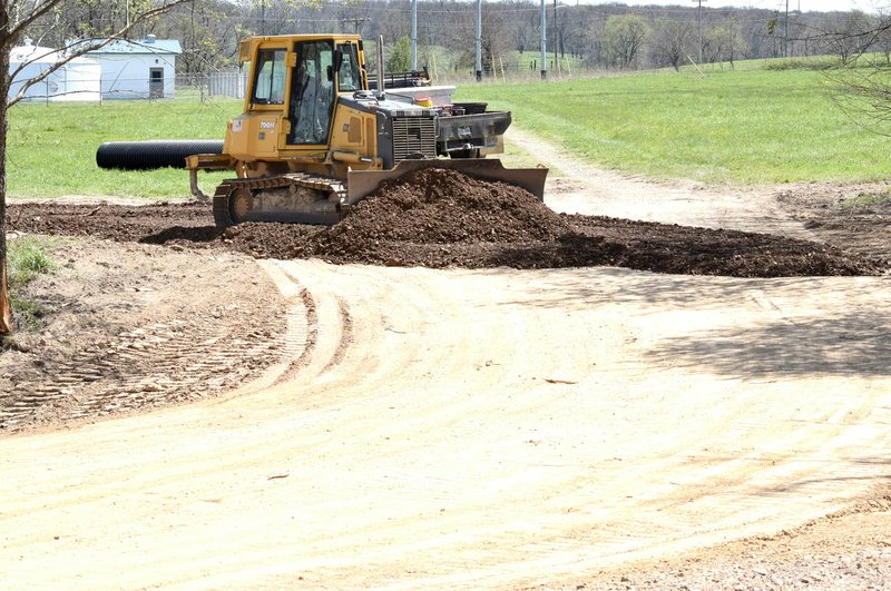 Westside Eagle Observer/MIKE ECKELS A bulldozer spreads a layer of dirt over an existing roadbed near the Grant Springs Apartment complex in western Decatur April 20. Recent heavy rains flooded the low-water bridge near the complex, trapping residents in their apartments for nearly 24 hours.