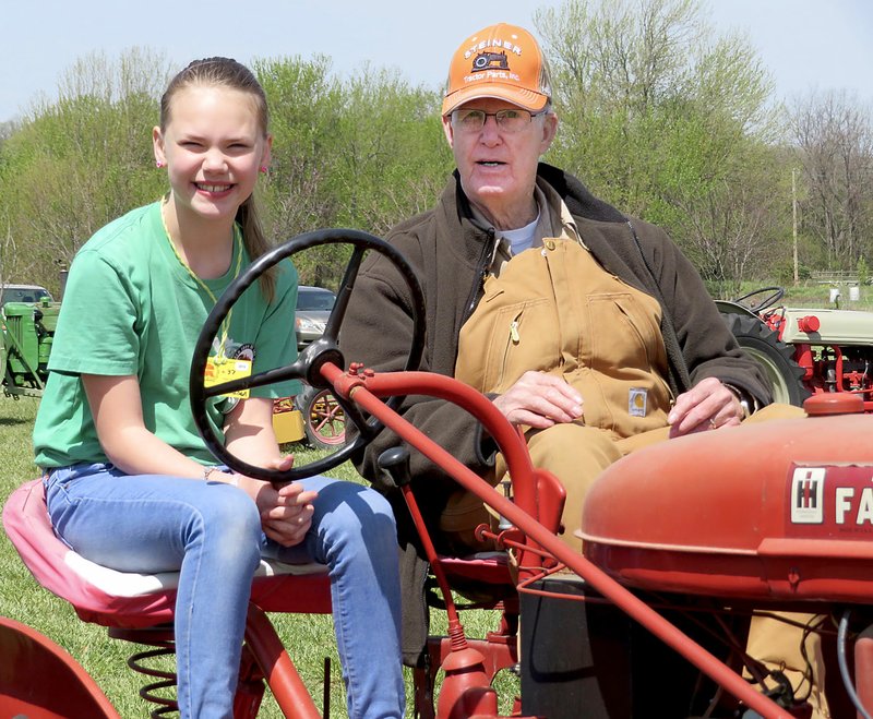 Westside Eagle Observer/RANDY MOLL Hailey Hodson, 10, of Bentonville, got a lesson from Glenn Smith of Gentry in tractor driving on one of his two-seater, double-controls tractors during the parade of power at noon on Friday (April 20, 2018) at the spring show of the Tired Iron of the Ozarks in Gentry.