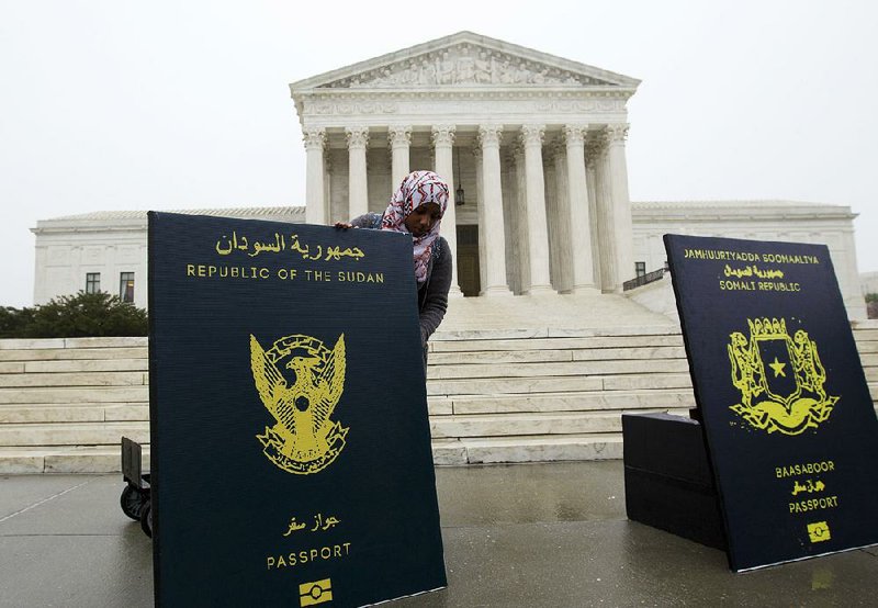 A protester sets up a display representing passports from countries that are subject to President Donald Trump’s travel ban during a rally Wednesday outside the Supreme Court building.