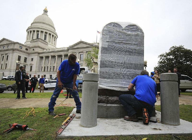 Employees from Wilbert Memorials install the new Ten Commandments monument Thursday at the state Capitol. The monument replaces one destroyed last year.  