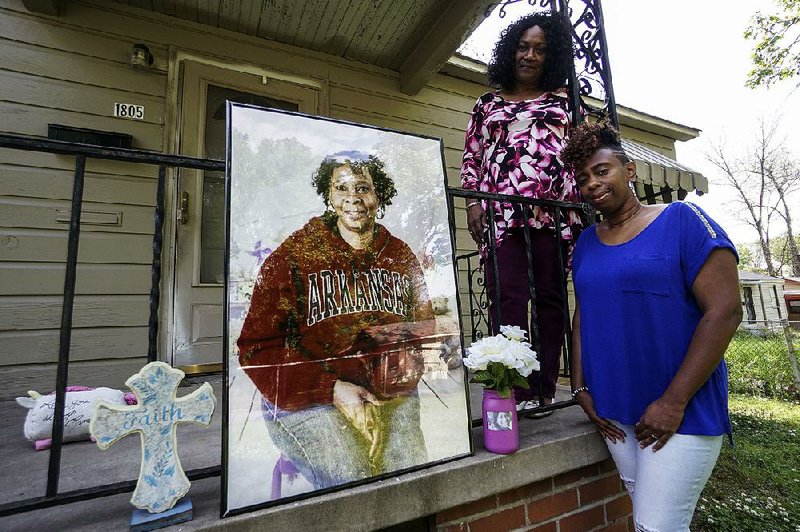 Shirley Jackson’s daughter, Takiela Spear, (right) and sister, Erma Sims, pose Wednesday with a photo of Jackson outside the Little Rock home where Jackson was killed a year ago today.  