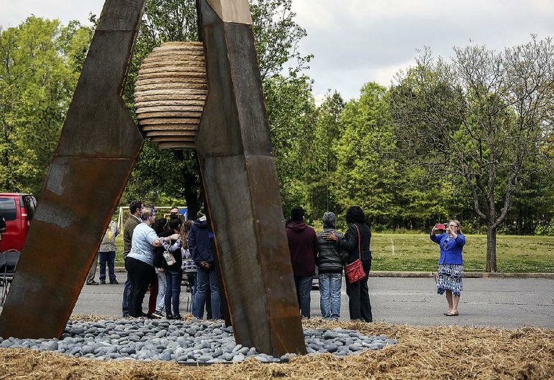 Karen Greenlee, assistant principal at Cloverdale Middle School, snaps a photo of students in front of Arkansas A , during a dedication ceremony Thursday for the sculpture on the grounds of Southwest Community Center in Little Rock. The 16-foot sculpture, created by Stephen Shachtman, was the winner of the 2017 Sculpture at the River Market.  