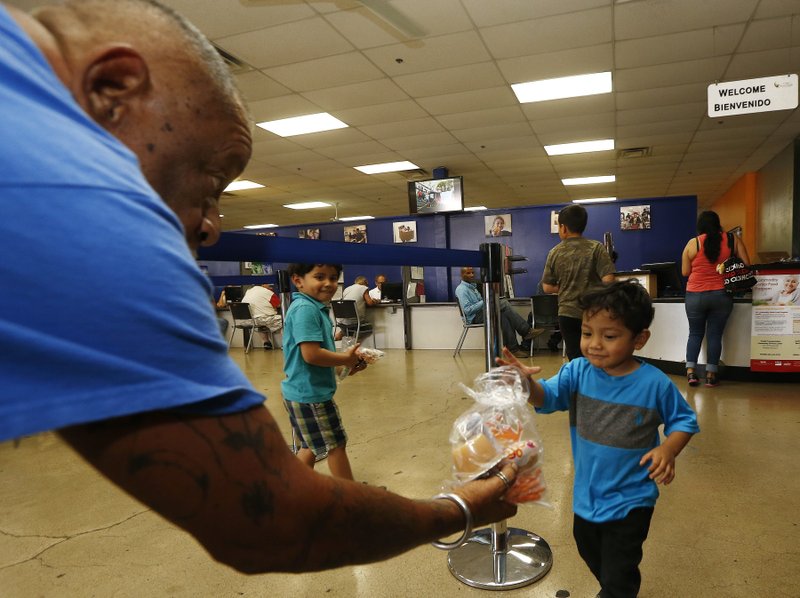 Volunteer Monroy Martinez, left, hands out a free to-go lunch to a young boy at the St. Mary's Food Bank Alliance due to the Arizona teachers strike Thursday, April 26, 2018, in Phoenix. (AP Photo/Ross D. Franklin)