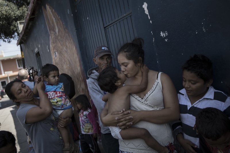 A mother and her child who are traveling with a caravan of Central American migrants wait in line for a free meal after arriving to the Juventudes 2000 shelter in Tijuana, Mexico, Wednesday, April 25, 2018. The caravan of mainly Central American migrants are planning to request asylum, either in the United States or Mexico. (AP Photo/Hans-Maximo Musielik)