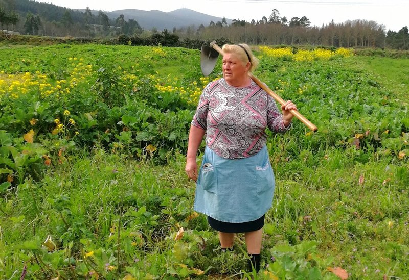Dolores Leis stands in a field on her farm in Galicia, in northern Spain, Thursday April 19, 2018. Leis, has found unexpected fame on social media after many found she bore a striking resemblance to U.S. President Donald Trump. Thousands of responses flooded in last week after a journalist reporting on farming in northwestern Spain posted on Instagram a picture of Dolores Leis dressed in farm clothing with a hoe over her shoulder. (Paula Vazquez via AP)