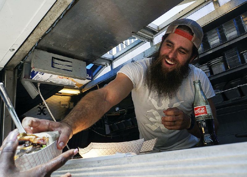 Arkansas Democrat-Gazette/MITCHELL PE MASILUN --4/27/2018--
Kyle Pounders, owner/operator of Excaliburger, serves up patrons during Food Truck Friday at Capitol Ave and Main street in downtown Little Rock Friday, April 27, 2018. The Food Trucks run through May 18.