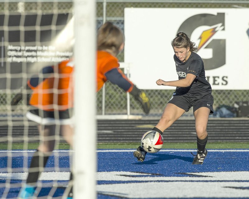 Bentonville High’s Anna Passmore (right) takes a shot Friday against Rogers High. Sara Roberts of Bentonville booted in the rebound for a goal after the shot at Whitey Smith Stadium in Rogers. 