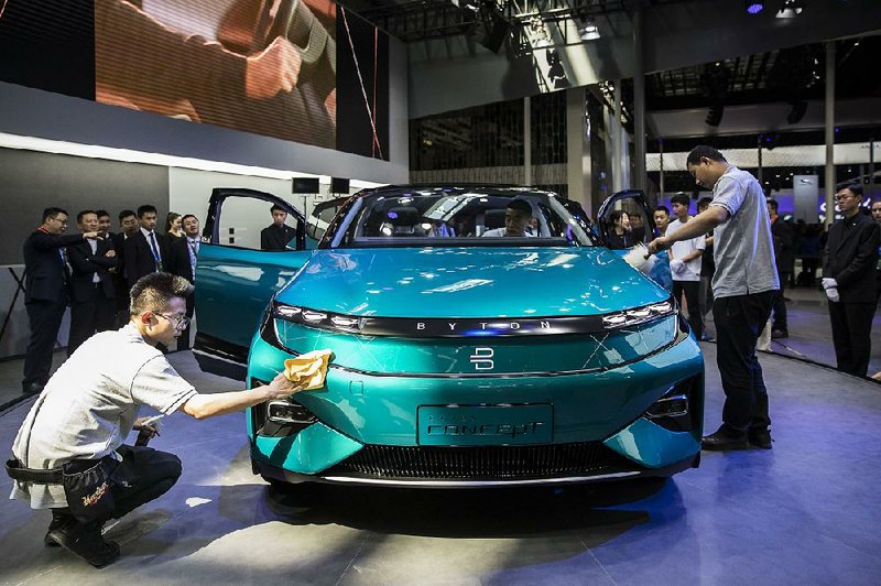 Workers clean a Byton electric concept vehicle on display last week at the Beijing International Automotive Exhibition in China. 
