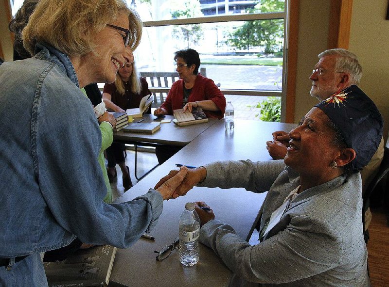 Author LaVerne Bell-Tolliver (seated) greets Audrey Evans as Bell-Tolliver signs books Sunday at the Arkansas Literary Festival after speaking about the early 1960s’ desegregation of junior high schools in Little Rock. 
