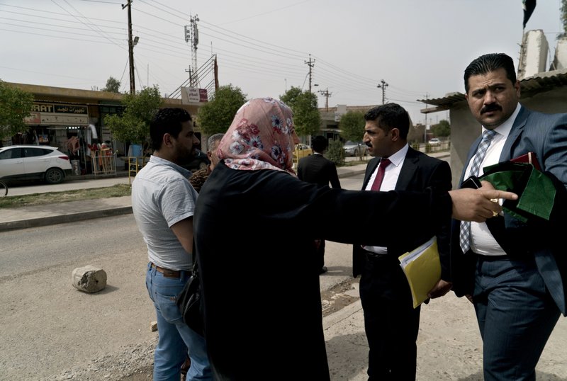 In this Wednesday, April 18, 2018 photo, Umm Kahtan talks to her son's lawyer after his sentencing was delayed outside the counterterrorism court in Tel Keif, Iraq. The 28-year-old doctor was detained in Mosul in 2017, accused of selling Islamic State propaganda materials. (AP Photo/Maya Alleruzzo)