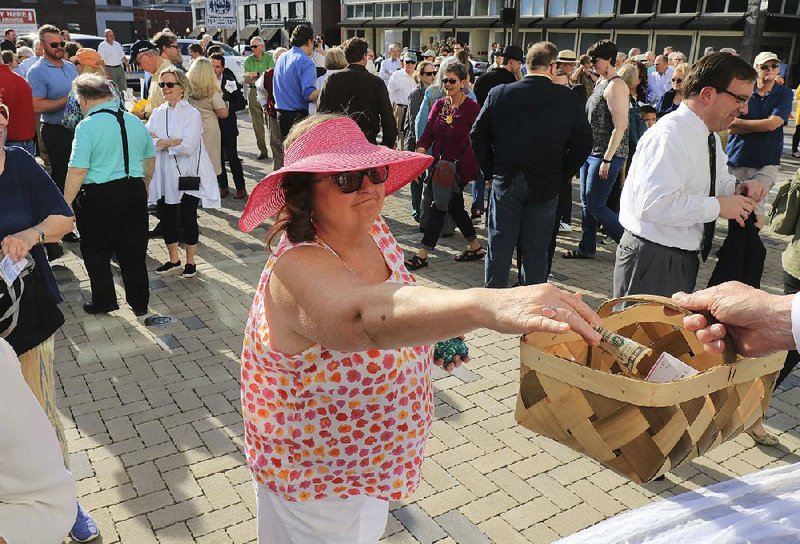 Dianne Estes of Little Rock drops money into a collection basket Tuesday afternoon during a fundraiser for the Arkansas Repertory Theatre outside the theater in Little Rock. 