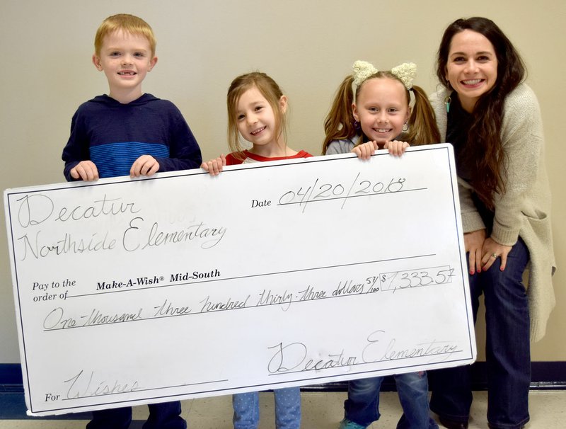 Westside Eagle Observer/MIKE ECKELS Logan Smith (left), Esme Gibson and Lauryn Taylor, students at Decatur Northside Elementary, present a check for $1,300 to Esther Schroeder, development manager for Make-A-Wish Foundation Mid-South April 19.