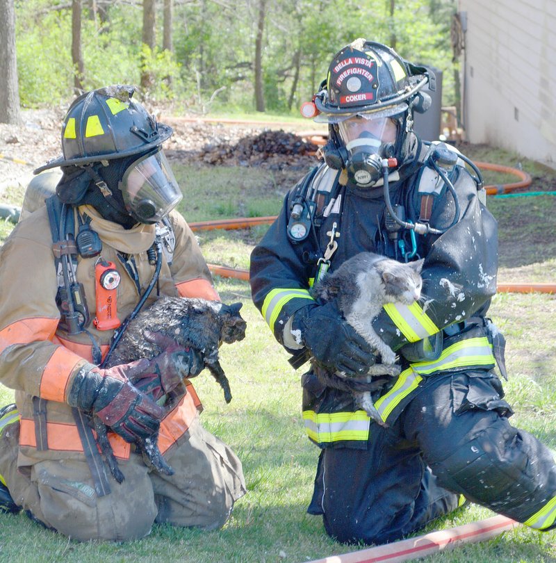 Keith Bryant/The Weekly Vista Firefighter-EMT Jason Young, left, sits with firefighter-paramedic William Coker after rescuing Ken and Janis Roper's cats, Missy and Bella, from their burning house at 3 Cheddar Drive.