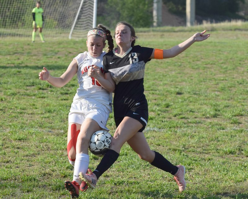 RICK PECK/SPECIAL TO MCDONALD COUNTY PRESS McDonald County's Ava Smith (left) battles a Neosho defender for control of the ball during the Lady Mustangs' 3-0 loss on Monday night at McDonald County High School.