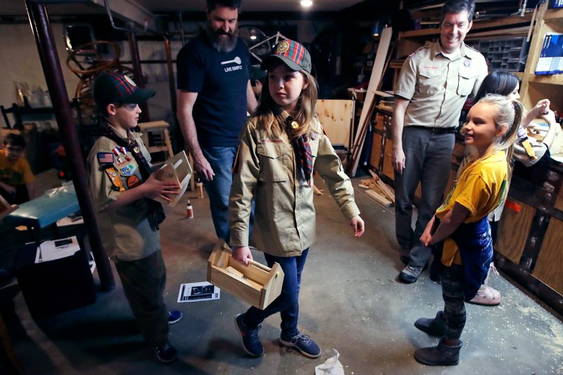 FILE - In this March 1, 2018, file photo, Tatum Weir, center, carries a tool box she built as her twin brother Ian, left, follows after a Cub Scout meeting in Madbury, N.H. Fifteen communities in New Hampshire are part of an "early adopter" program to allow girls to become Cub Scouts and eventually Boy Scouts. For 108 years, the Boy Scouts of America's flagship program for older boys has been known simply as the Boy Scouts. With girls soon entering the ranks, the BSA says that iconic name will change to "Scouts BSA" The change will take effect in February 2019. (AP Photo/Charles Krupa, File)
