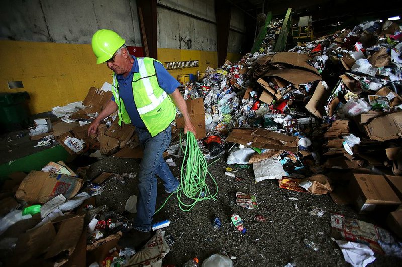 FILE - Arkansas Democrat-Gazette/THOMAS METTHE -- 5/3/2018 --
Rusty Miller, plant manager for the Waste Management Little Rock Recycling Facility pulls an extension cord out of a pile of recyclable material waiting to be sorted at the plant on Thursday, May 3, 2018, in Little Rock.